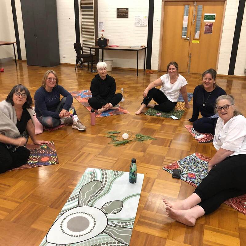 Six women in activewear sitting in a circle on yoga mats at the end of a Qoya class for adults in Gisborne, Victoria.