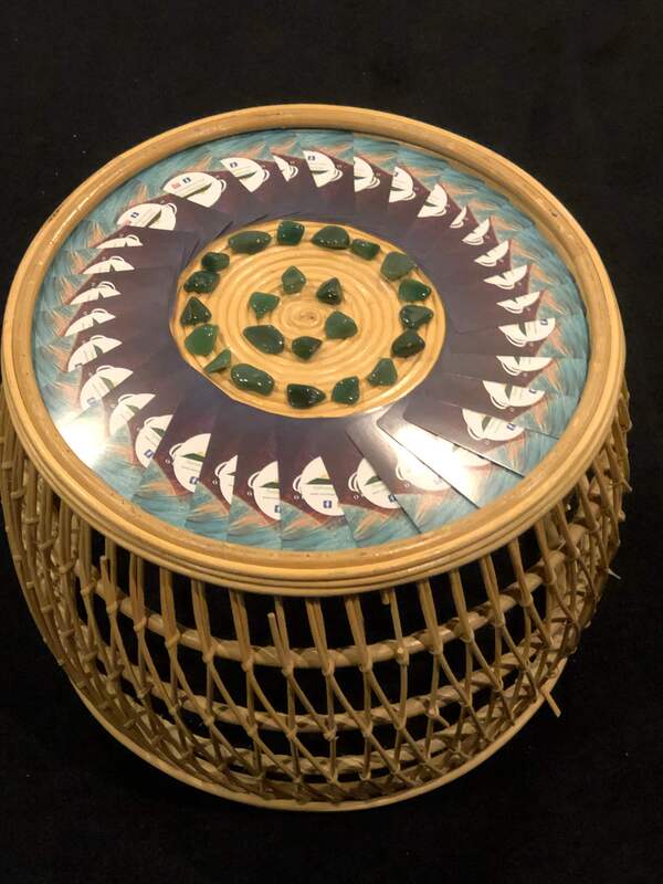 A small circular cane table with an altar on it. There are green crystals in two circles in the middle and then surrounded by a ring of oracle cards. 